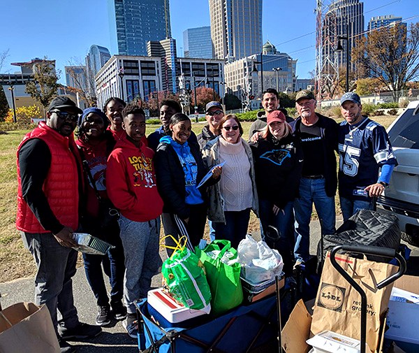 The founding Hearts to Hands serving hearts gathered on Thanksgiving morning, 2018, in front of the uptown Charlotte skyline
